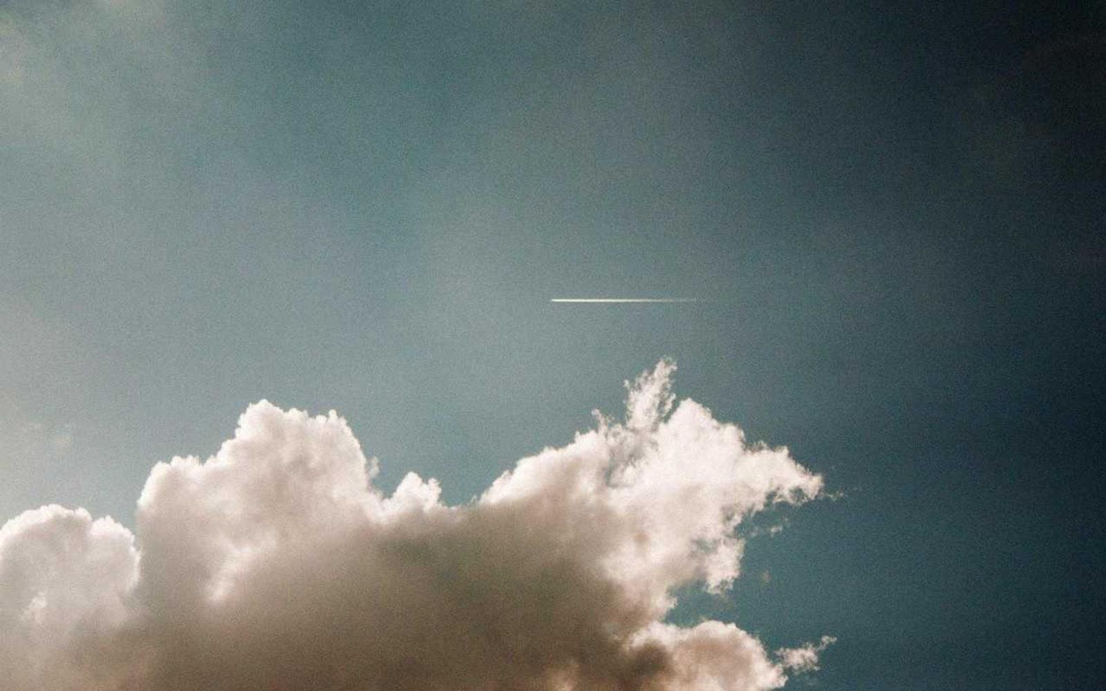 A white cumulus cloud in a dark teal sky