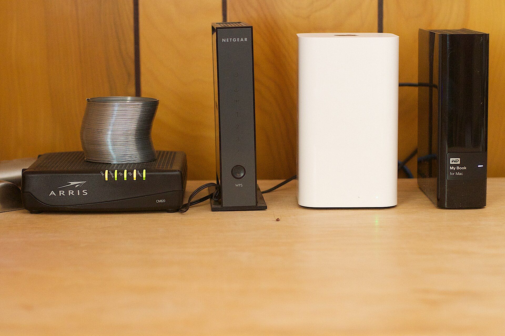 A shelf at home with a modem, a router, a Wi-Fi base station and an external hard drive